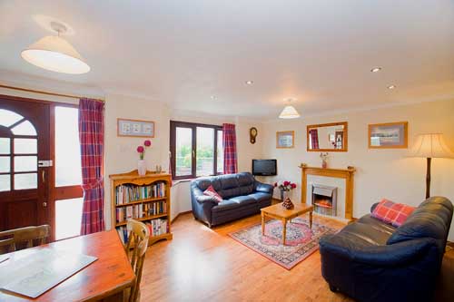 Bramblewood's sitting room with leather sofas and local prints by artist Harry McConville
